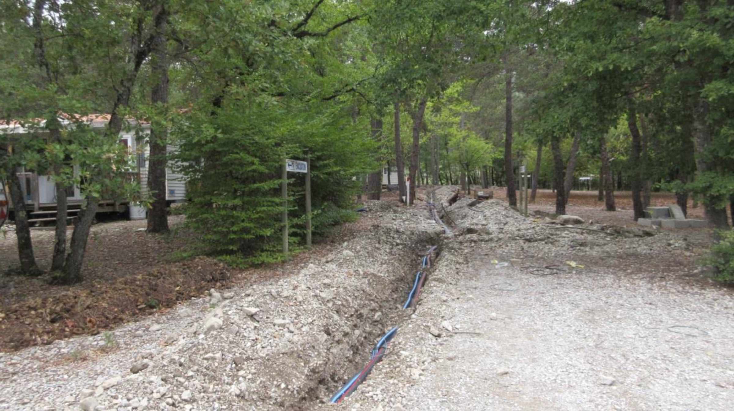 Vue longue des tranchées de raccordement sous la canopée du camping La Ruche